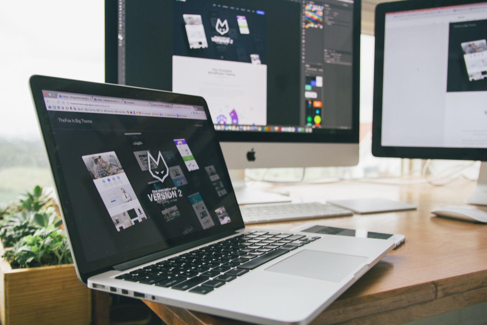 Notebook e monitores mostrando o layout de um site em construção