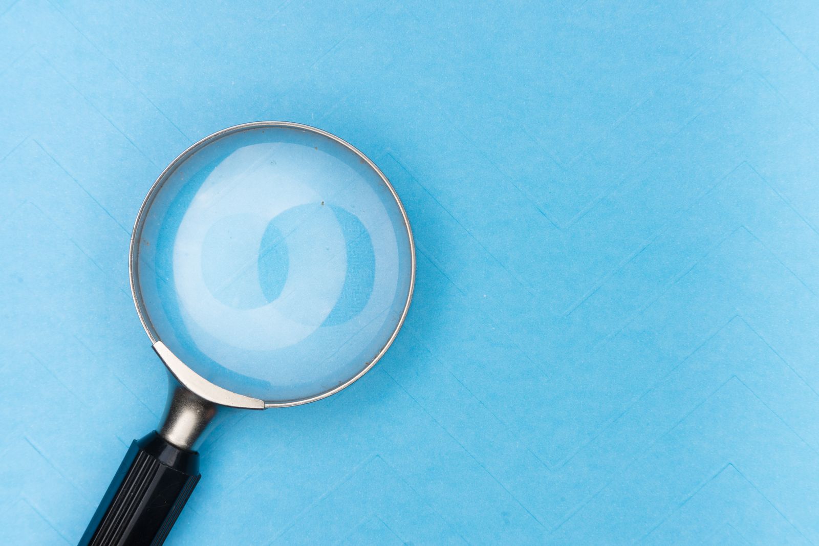 Lupa sobre uma superfície azul vazia, sem nada para encontrar